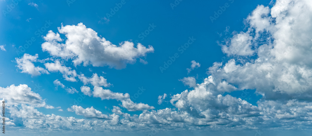 Daytime blue sky Background with white cumulus clouds . Panoramic cloudscape.