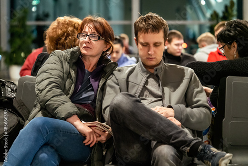 Tired man and woman are sitting in the waiting room of the international airport