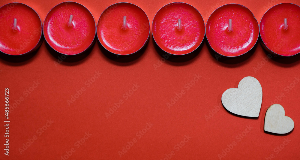 Red small candles on a red background with wooden hearts with space for text Red small candles on a red background with wooden hearts with space for text