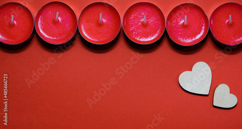 Red small candles on a red background with wooden hearts with space for text