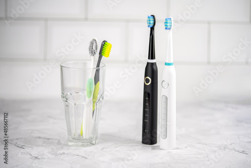 Electric and regular toothbrush in a bathroom. Dental care. Manual toothbrush against modern electric toothbrush concept.