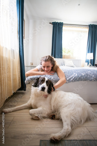 woman and white dog waking up in bedroom