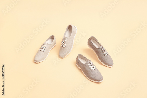 Stylish gray color sneakers isolated on beige background; space for text; perspective view