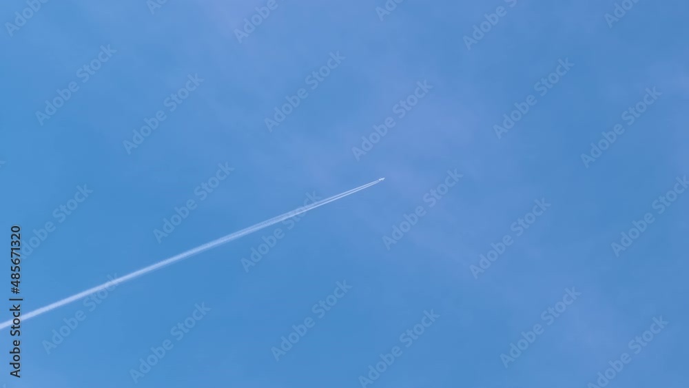 Distant passenger jet plane flying on high altitude on blue sky with white clouds leaving smoke trace of contrail behind. Air traveling concept Distant passenger jet plane flying on high altitude on blue sky with white clouds leaving smoke trace of contrail behind. Air traveling concept