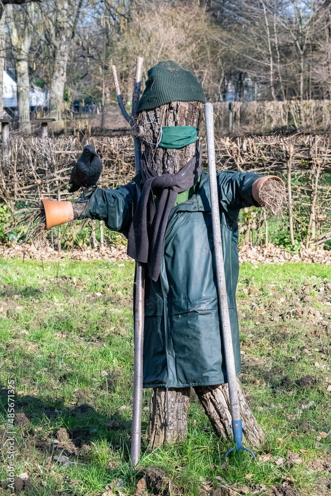 Naklejka premium A scarecrow in a field, with a crow perched on his arm 