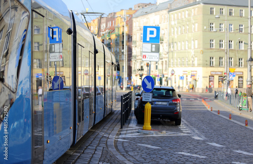 Tramwaj i samochód osobowy na drodze w centrum Wrocławia, odbicie.