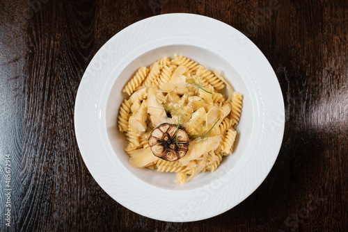 Pasta with cheese and herbs garnished with fried garlic.
