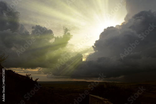 Cloudscape image of dark stormy clouds in blue sky with sun beam. The rays of the sun after the rain. Scenery with the sun's rays filtering through the gray clouds. Dramatic sky as the sun hides 
