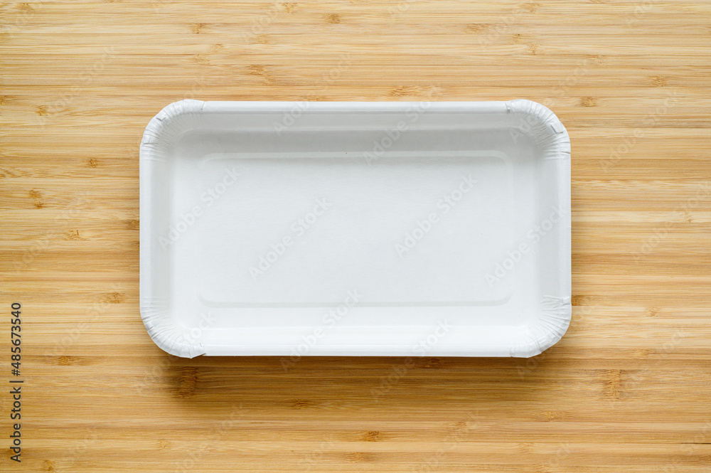 Rectangular white disposable empty plate on a wooden background. View from above. Rectangular white disposable empty plate on a wooden background. View from above.