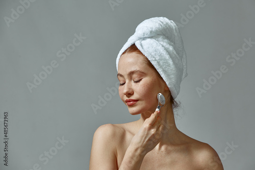 Girl massaging face contour by jade roller massager. Woman do facial massage. Rejuvenation, antiaging skincare treatment