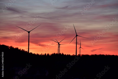 Windkrafträder in einem Windpark mit Abendrot und dunklen Wolken