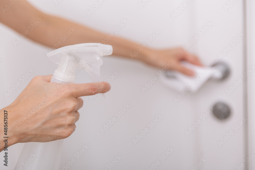 Cleaning white door handles with an antiseptic wet wipe and sanitizer spray. Disinfection in hospital and public spaces against corona virus. Woman hand using towel for cleaning home room door link Cleaning white door handles with an antiseptic wet wipe and sanitizer spray. Disinfection in hospital and public spaces against corona virus. Woman hand using towel for cleaning home room door link