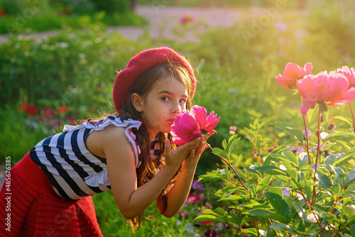 Little girl in the park holding a big pink peony