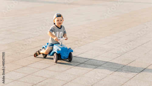 Little boy rides on a toy car in the park, happy child on a sunny summer day, driving a car outdoors © Shopping King Louie