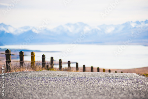 Close up detail of mountain road with snow capped mountains and lake landscape at Tekapo, South Island New Zealand