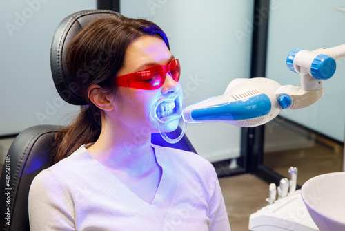 A young woman receives a teeth whitening procedure at a dental clinic