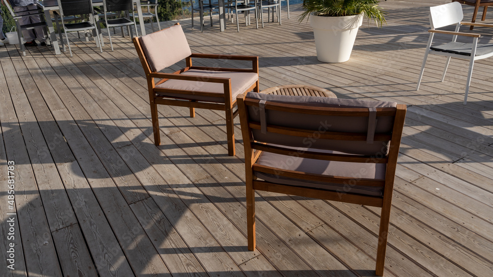 Wooden table and chairs on the summer terrace during sunshine weather 