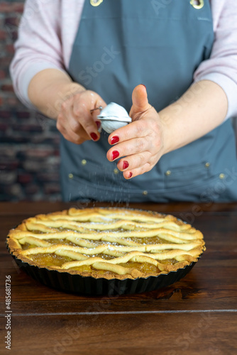 Women preparing delicious apple tart or pie large on wood table background.