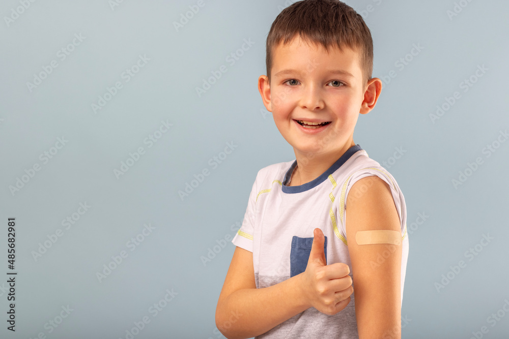 Vaccinated boy gesturing with thumbs up, showing hand with plaster cast after injection of coronavirus vaccine. Start of vaccination campaign for children and teenagers Vaccinated boy gesturing with thumbs up, showing hand with plaster cast after injection of coronavirus vaccine. Start of vaccination campaign for children and teenagers