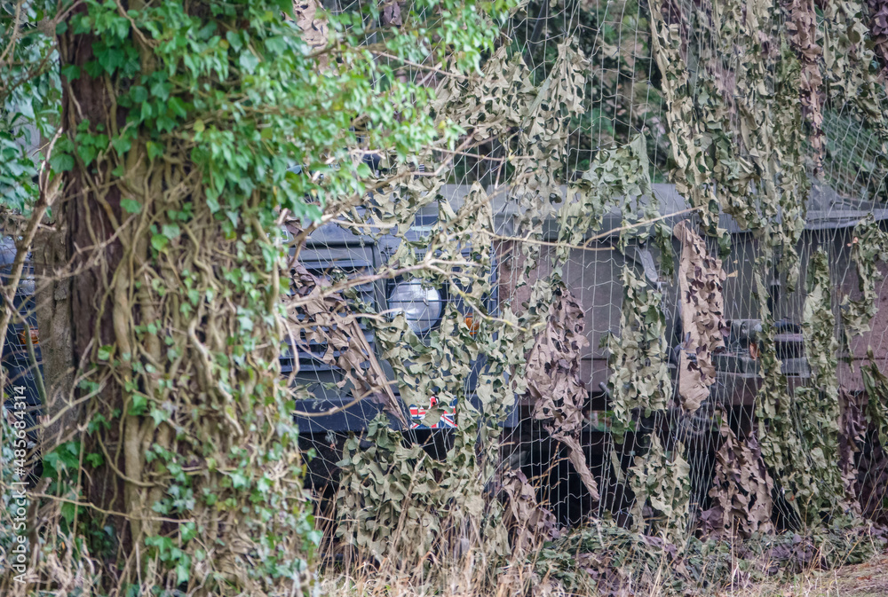 a british army land rover defender wolf medium utility vehicle camouflaged and hidden amongst woodland on a military exercise, Wiltshire, UK a british army land rover defender wolf medium utility vehicle camouflaged and hidden amongst woodland on a military exercise, Wiltshire, UK