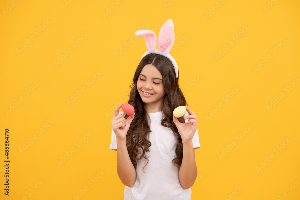 positive child in bunny ears hold eggs on yellow background, happy easter.