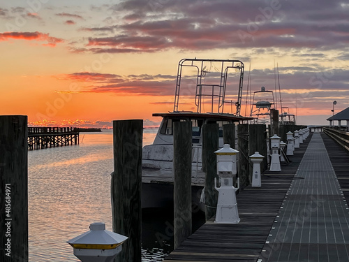 Fotografia A colorful orange sunrise over the pier in Apalachicola, Florida with old, docked boats