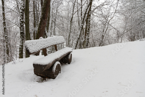 The bench covered with snow in the Italian alpine forest