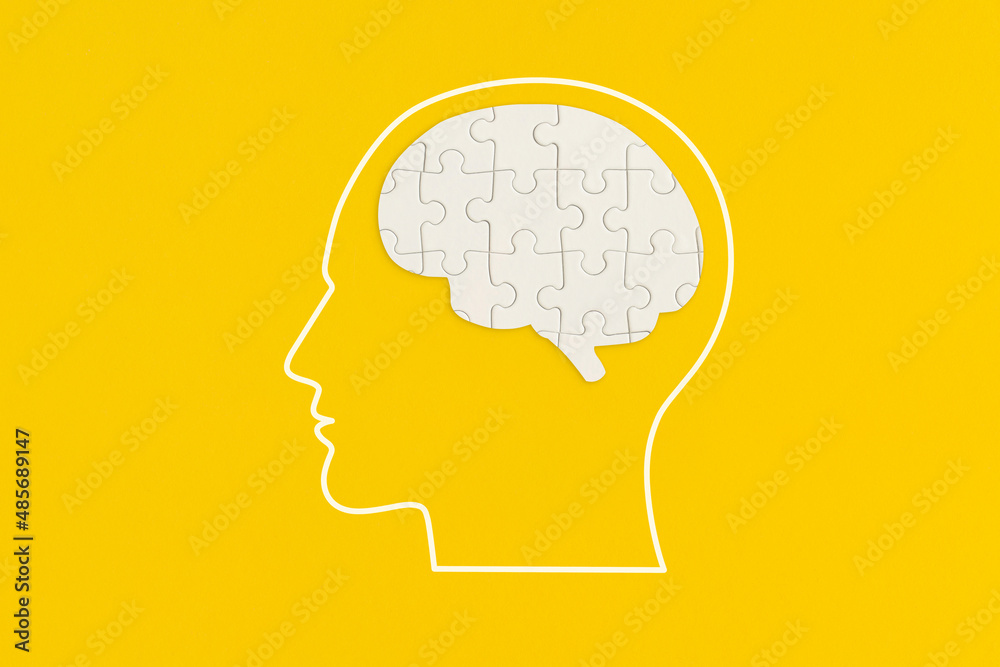 Human head with puzzle on yellow background