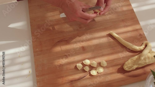 Close-up of hands making homemade pasta according to a traditional recipe from the southern Italian region. Orecchiette products are in the form of flattened discs no larger than 2 cm in size.