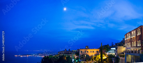 Mount Etna Volcano and the moon at night  panoramic view seen from Piazza IX Aprile on Corso Umberto  the main street in Taormina  Sicily  Italy  Europe