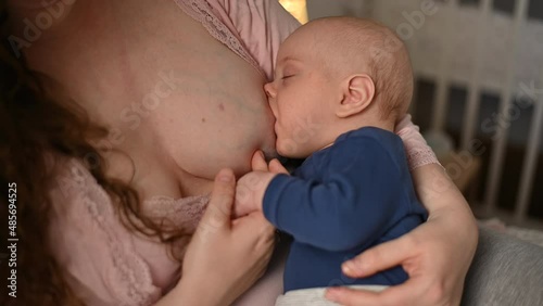 Mother breastfeeding her baby boy and putting him to sleep
