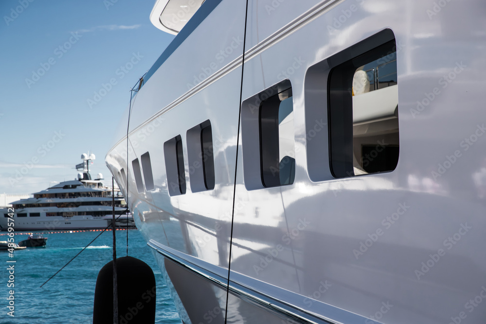 Naklejka premium The top deck of a huge yacht at sunny day, glossy board of the boat, The chrome plated handrail, megayacht is moored in port, sun reflection on glossy board