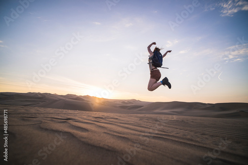 Woman jumping at sunset in the desert at Huacachina, Ica Region, Peru, South America © Matthew