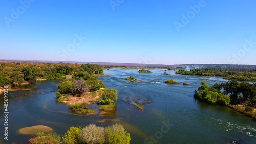 Aerial view of the Zambezi River flowing around Victoria Falls, showcasing dramatic waters, lush surrounding landscapes, and the iconic waterfall. Ideal for nature, travel, and adventure projects.