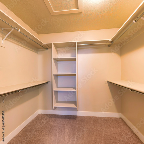 Square Empty walk-in closet with warm color lighting and shelving units
