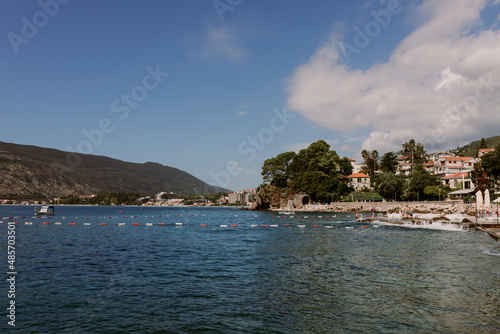 Herceg Novi, Montenegro - 15.09.202: bathing people in the Bay of Kotor on the Adriatic sea coastline at sunny day, mediterranean landscape. Famous tourist destination, leisure and weekend concept