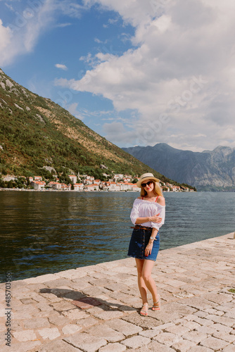 Lady on the island in The Bay of Kotor, the Adriatic Sea in southwestern Montenegro. Its well-preserved group of medieval towns. Travelling and leasure concept, beautiful seascape. Row of mountains