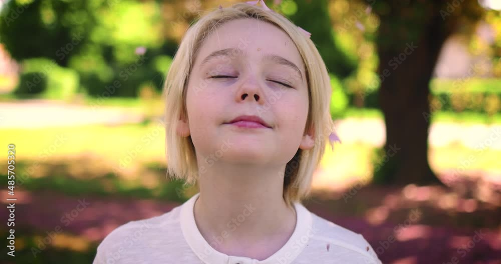 happy blond boy under the rain of blossoms in spring park at sunny day happy blond boy under the rain of blossoms in spring park at sunny day