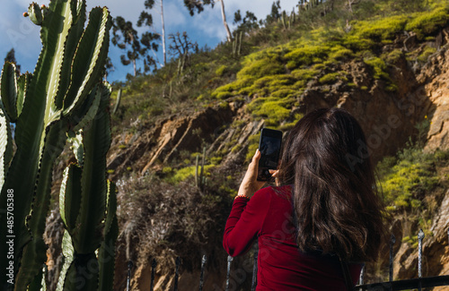 unrecognizable woman in red t-shirt taking photos of a mountain in Acobamba, Tarma, Peru. photo