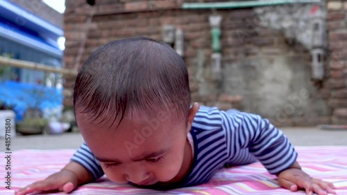 An Infant baby boy is lying on the floor doing mischief. The cutest infant baby is having fun lying on the floor. Portrait of a cute baby boy. Close-up view. photo