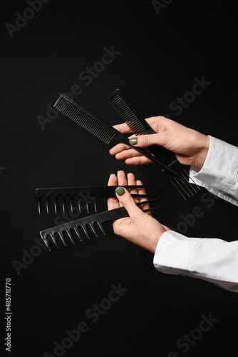Female hands with hair combs on dark background