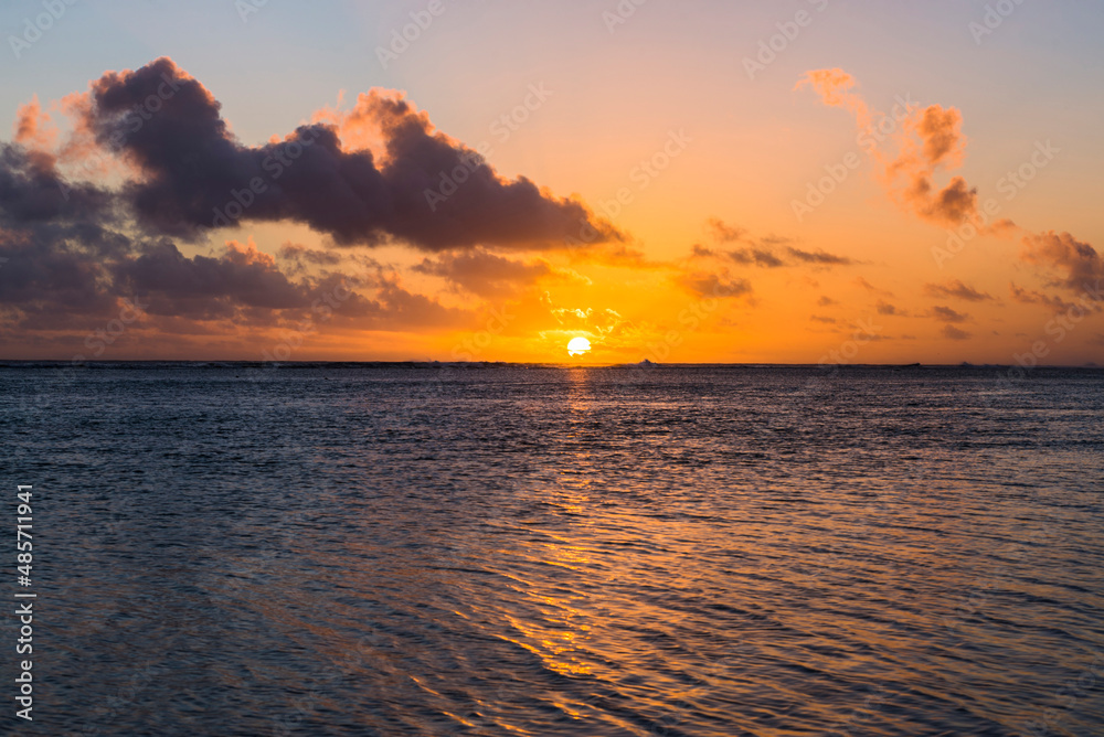 Tropical sunset background with copy space showing dramatic clouds in the sky over a horizon of the Pacific Ocean, Rarotonga, Cook Islands
