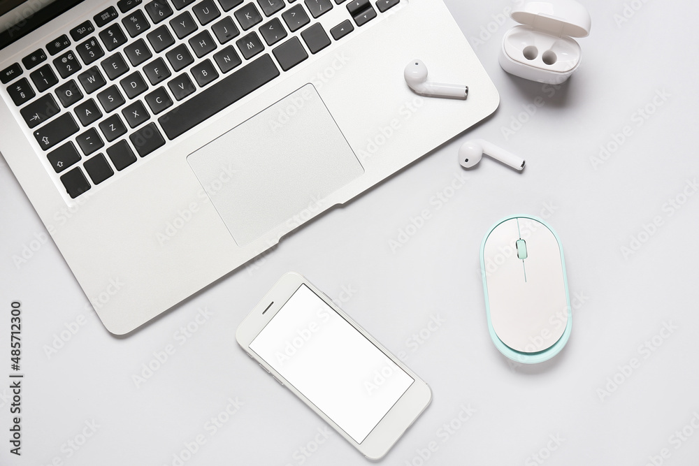 Modern laptop, mobile phone, earphones and PC mouse on white background, closeup Modern laptop, mobile phone, earphones and PC mouse on white background, closeup