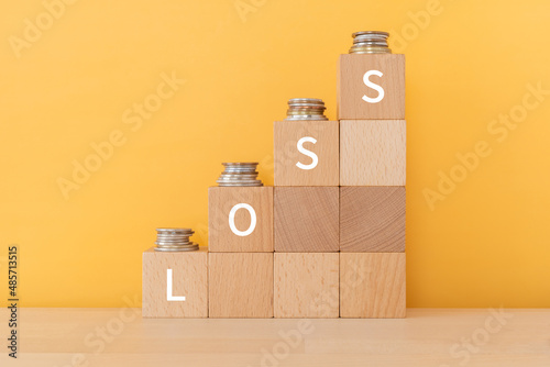 「LOSS」と書かれた積み木とコイン