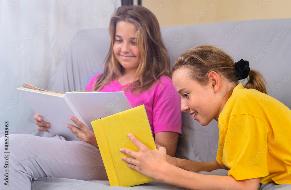 Girls are sitting on the couch and reading books Girls are sitting on the couch and reading books