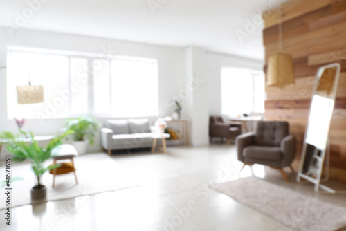 Blurred view of light living room with mirror and stylish furniture