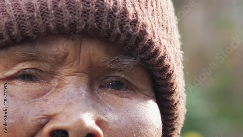 Close up sad eyes of asian elderly native woman look to camera. Senior female feel lonely, hopeless, unhappy. Concept of people rural lifestyle, northern Thailand, sadness, emotion, expression.