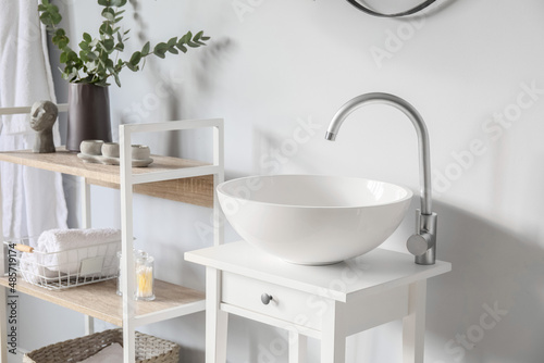 Small table with sink near light wall in bathroom