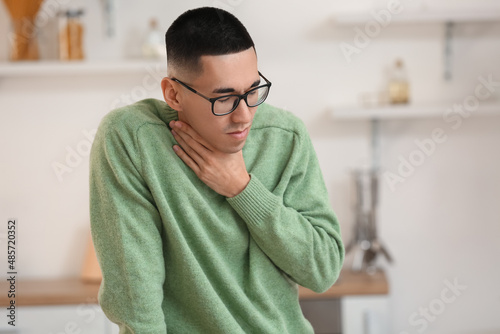 Ill Asian man with sore throat at home photo