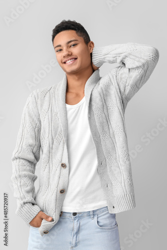 Handsome African-American guy in knitted sweater on light background